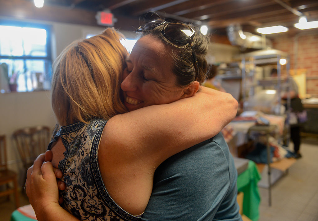Rostine hugs her friend Leah Bartlett goodbye